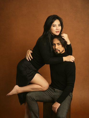 Stylish couple posing intimately against a brown backdrop.