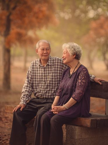 Elderly couple sitting on a bench enjoying a warm autumn day.