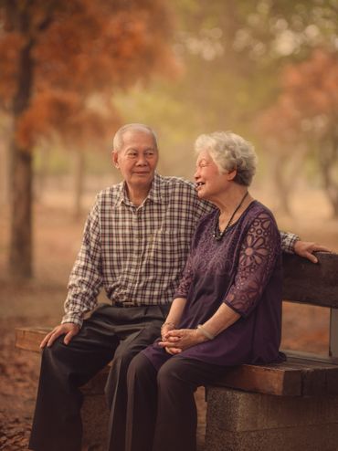 Elderly couple enjoying a peaceful moment on a park bench in autumn.