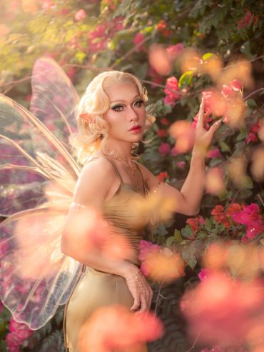 A fairy-like figure with delicate wings amidst vibrant flowers.