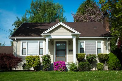 Charming small house with a well-maintained garden and green lawn.