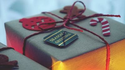 Wrapped gift with holiday red ribbon and a tag reading Seasons greetings.