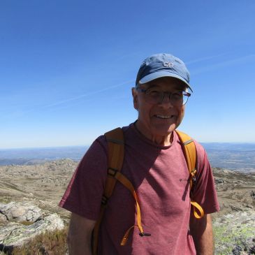 Smiling man hiking in a rocky landscape under a clear blue sky.