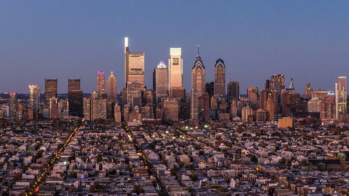 Twilight view of a sprawling city skyline with illuminated streets and tall buildings.