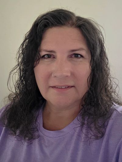 Woman with curly dark hair wearing a lavender shirt.