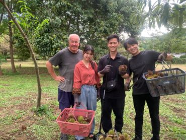 Group holding baskets of fruit outdoors.