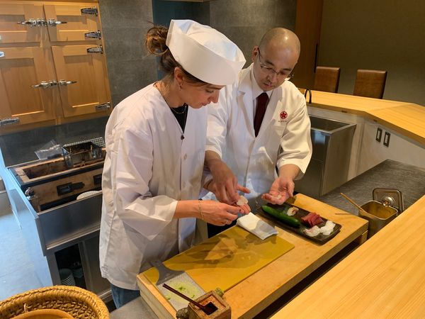 Two chefs preparing sushi together in a kitchen.