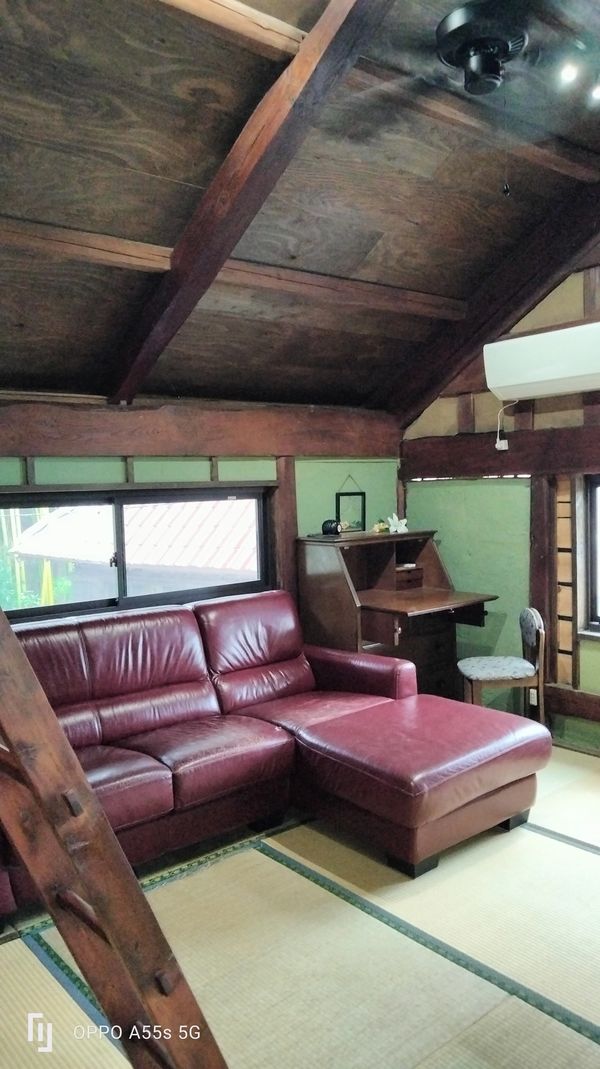 Cozy room with maroon leather sofa and wooden ceiling.