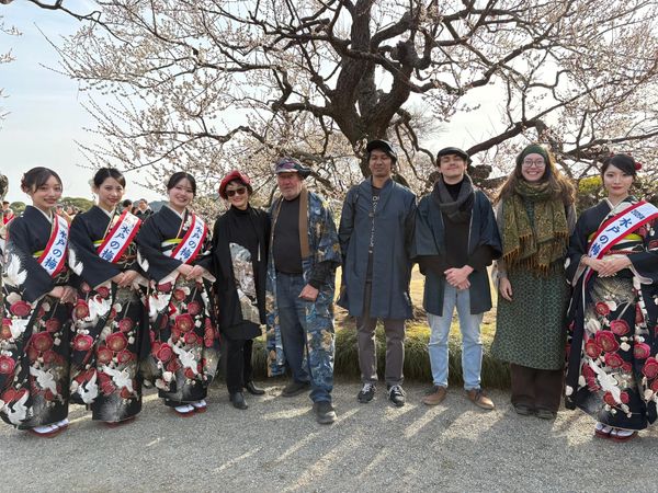 A group of people posing outdoors under a blooming tree.