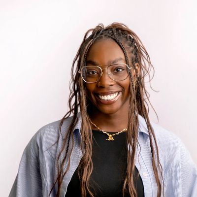 Smiling woman with long brown hair in braids. She is wearing glasses.