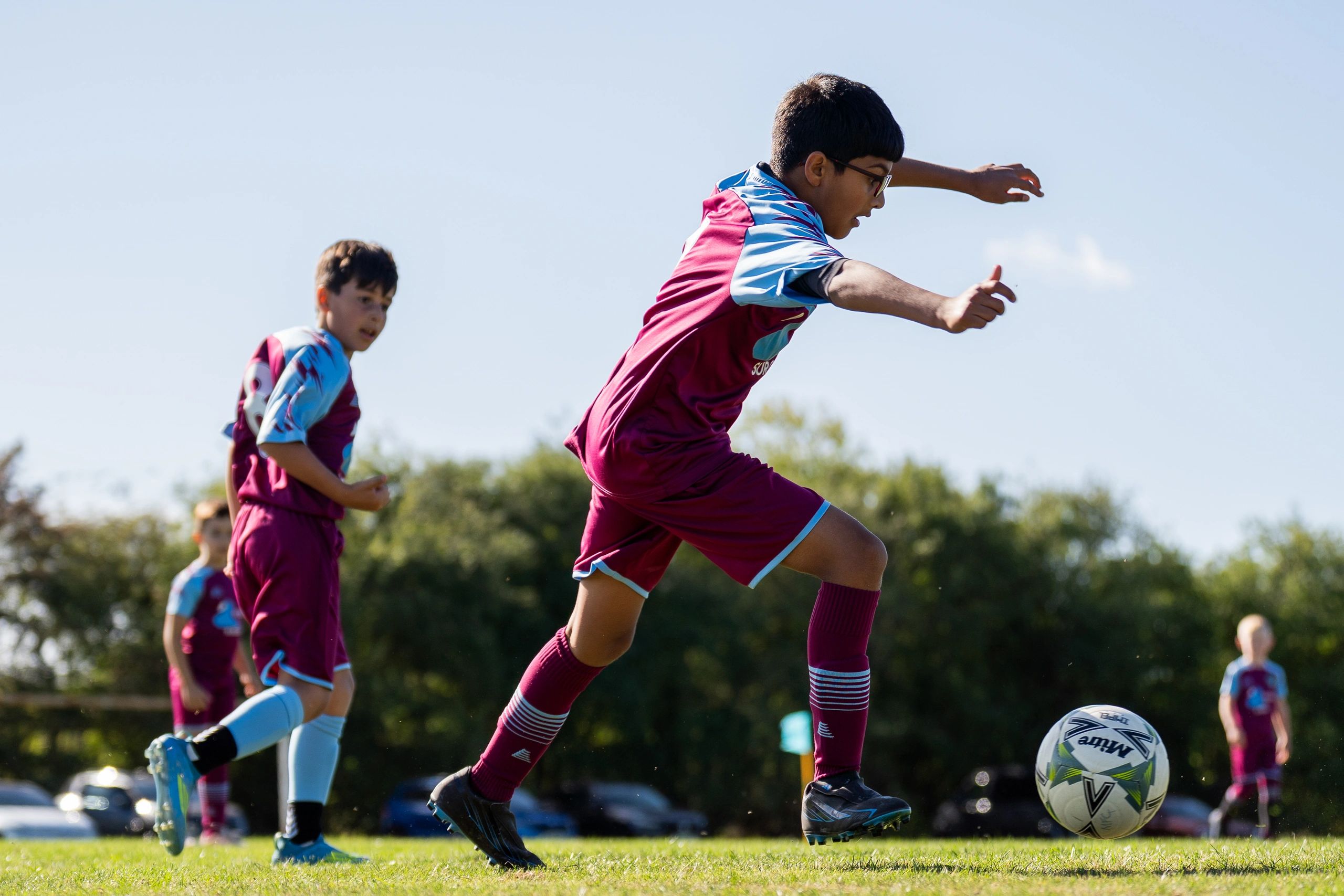 Young boys playing soccer outdoors on a sunny day.
