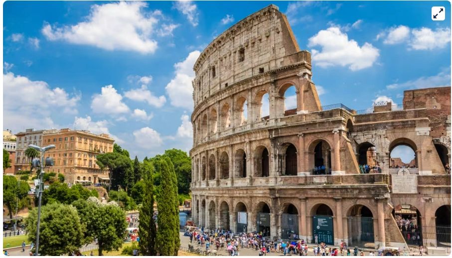The Colosseum in Rome under a bright blue sky with tourists around.