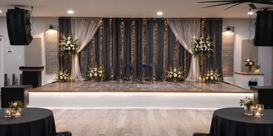 Elegant stage setup with floral arrangements and chairs.