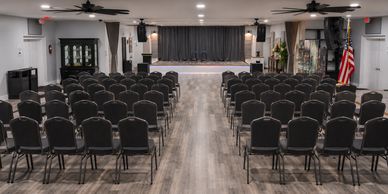 Empty conference room with rows of chairs facing a stage.
