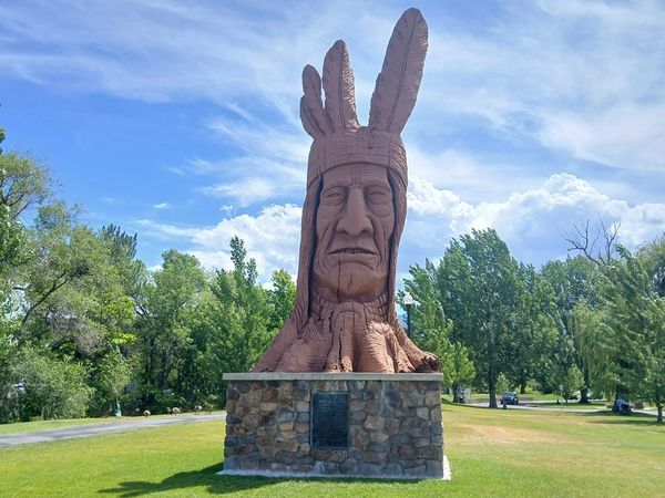 Statue of a Native American chief with feathers on his head.