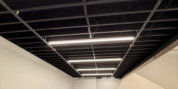 Modern ceiling with exposed beams and fluorescent lights.