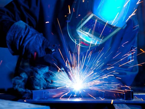 Worker welding with sparks flying.