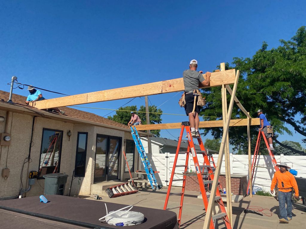 Construction workers installing wooden beams on ladders outdoors.