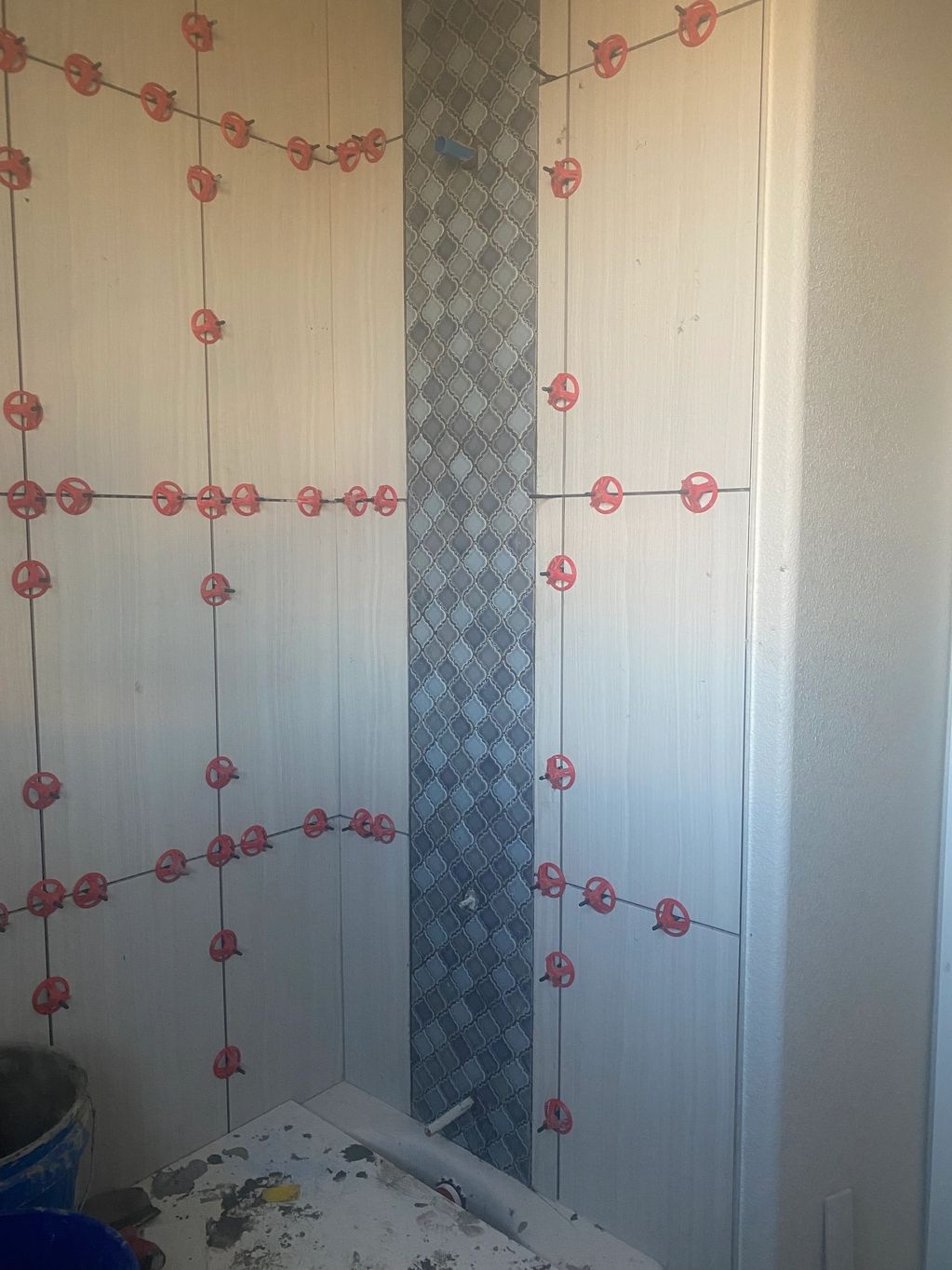 Wall tiles being installed with spacers in a bathroom corner.