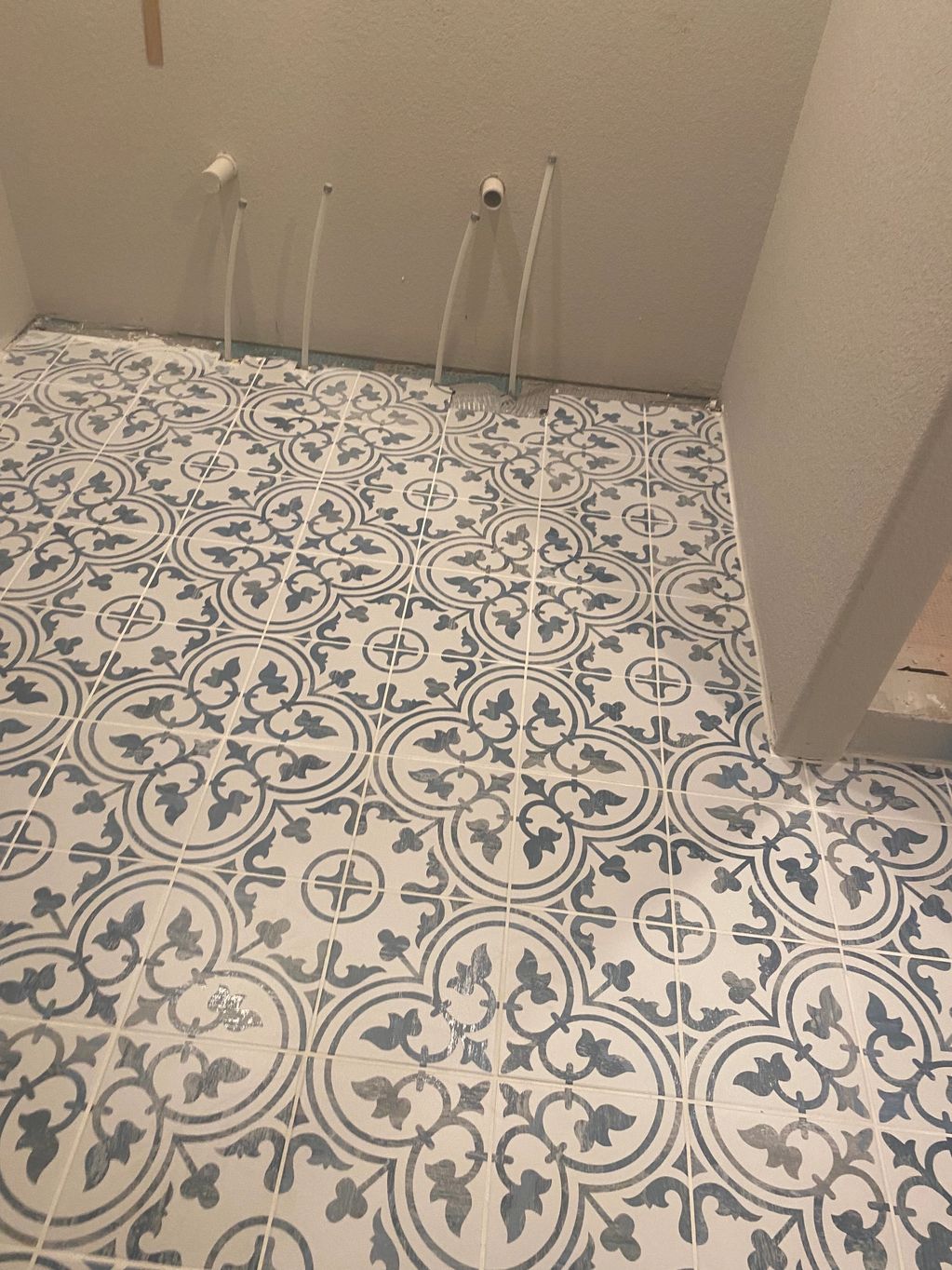 Newly tiled floor with intricate blue and white patterns in a room under construction.