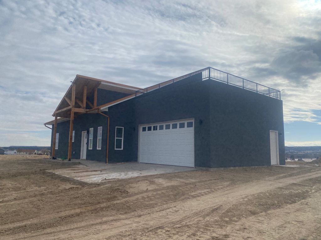 One of our custom builds provided in our construction services, Modern dark gray house with wooden porch and rooftop railing.