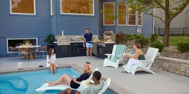 Large group of people at the pool relaxing and grilling food at outdoor kitchen