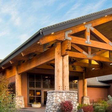 Rustic wooden house entrance with stone pillars.