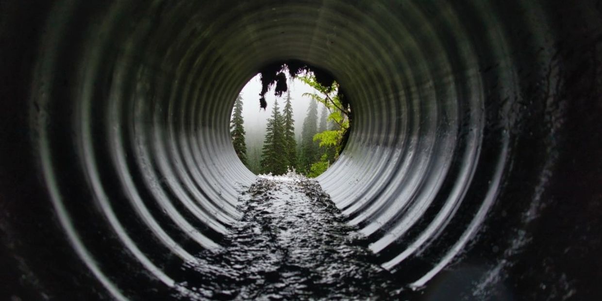 Sewer pipe with water flow representing active plumbing system in Airdrie home.