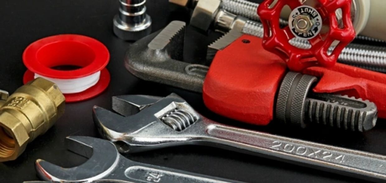 Plumbing tools laid out on black background. 