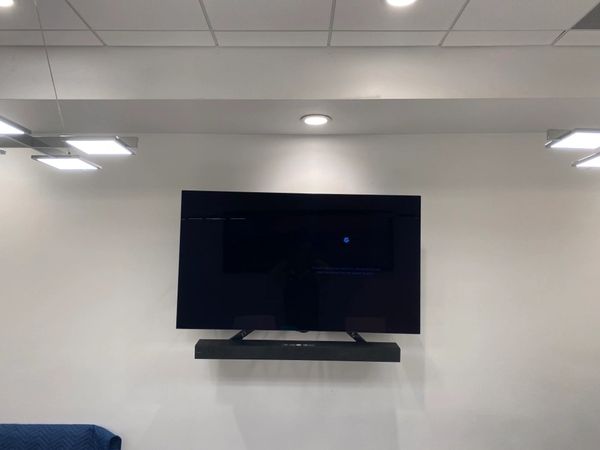 TV and a  soundbar installed with an electrical outlet behind.