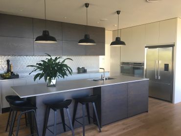 Modern kitchen with island and black stools.