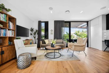 Modern living room with neutral decor and large windows.