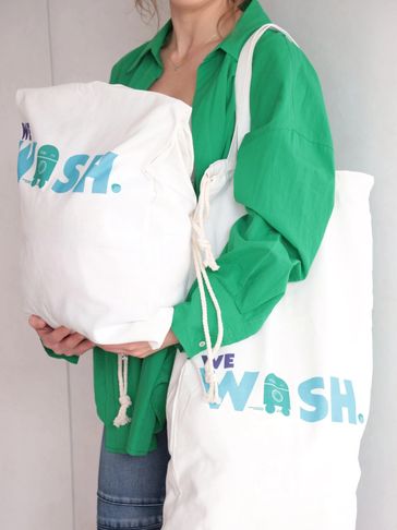 Person wearing green shirt holding white bags with blue text.
