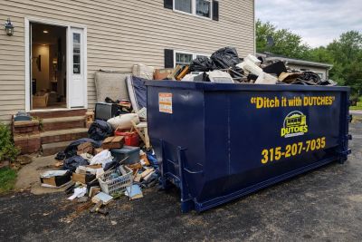 Dumpster overflowing with trash outside a house.