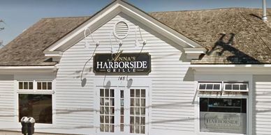 Exterior of a white wooden restaurant called Nana's Harborside Grill.