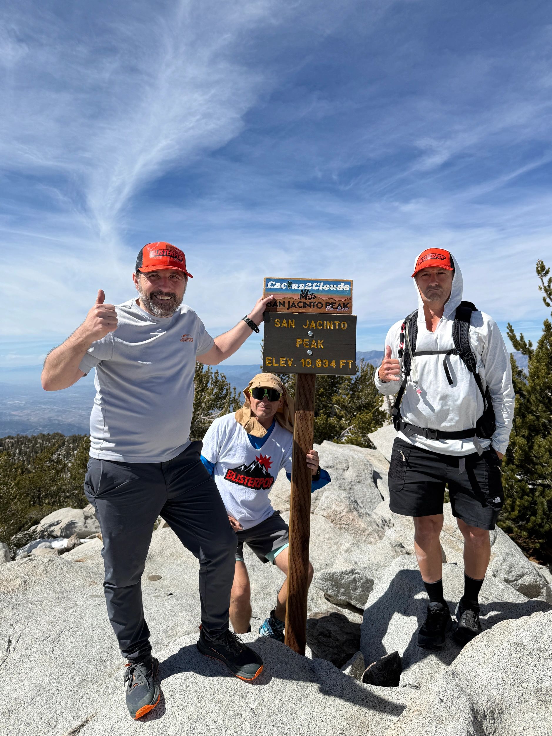 Three hikers posing by the San Jacinto Peak sign.