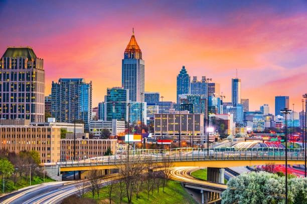 Vibrant city skyline at sunset with busy highways and colorful sky.