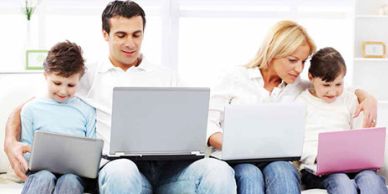 Family of four using laptops together.