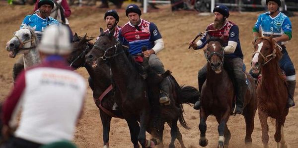 Men playing a horseback sport with sticks.