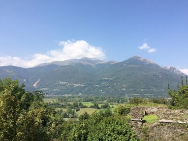 A scenic mountain range with lush greenery and a clear blue sky.