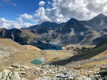 Mountainous landscape with two lakes under a partly cloudy sky.