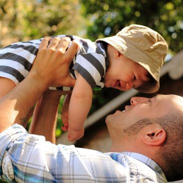 A father holding his son over his head at a birthday party