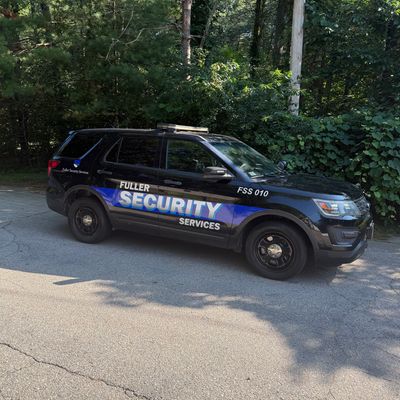 Black SUV security vehicle parked near greenery.