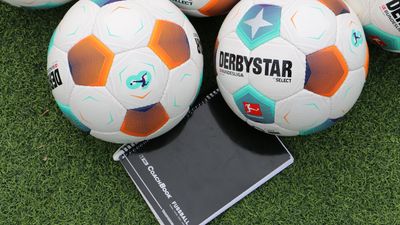 Fünf Derbystar-Fußbälle auf Gras mit Notizblock.