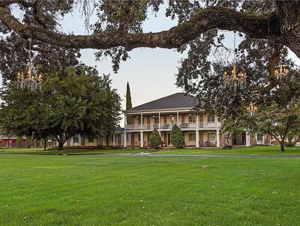 Large two-story house with a green lawn and trees.