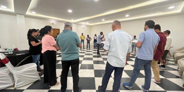 Group of people standing in a circle indoors.