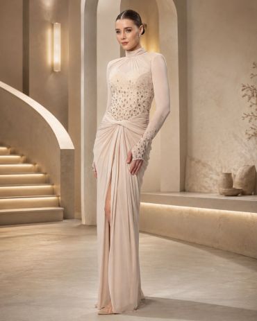 Elegant woman in a light beige embellished gown with long sleeves.