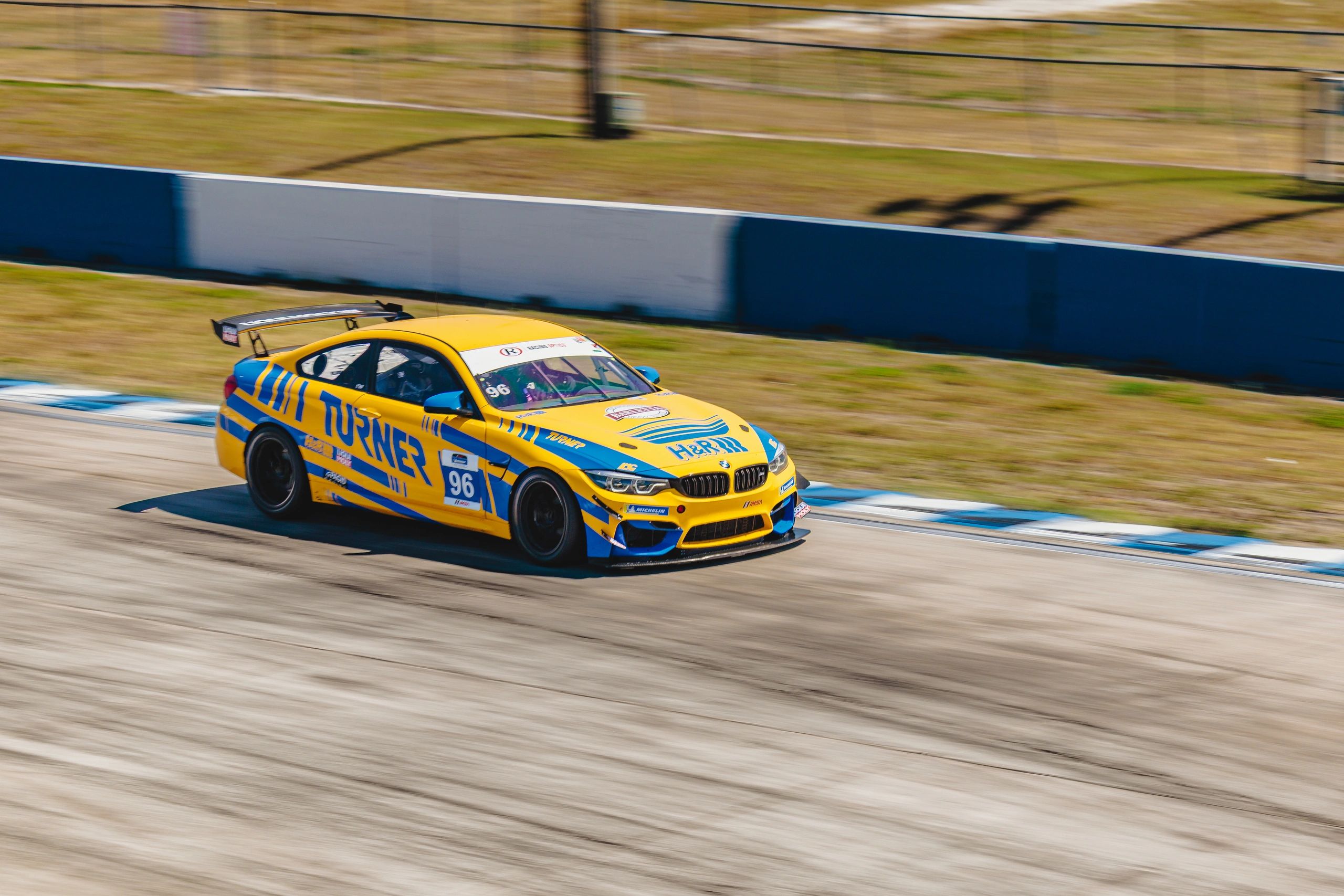 Turner Motorsport BMW M4 GT4 speeding on a racetrack at the Road2racers driving experience.