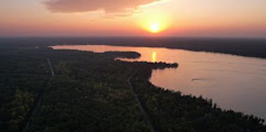 Sunset over a river winding through a forested landscape.