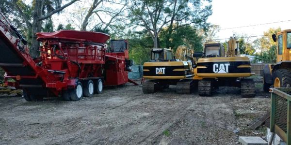 Construction site with heavy machinery including red equipment and two CAT excavators.